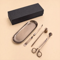 Bronze wick trimmer, candle snuffer, dipper and matching tray pictured beside a black box.